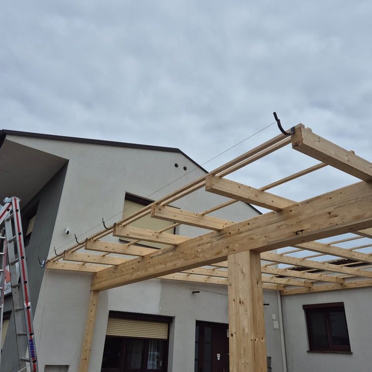 Ein Holzunterbau für ein neues Dach wird errichtet, während an der Fassade eines Hauses Dachrinnenhalter angebracht sind – Teil einer laufenden Dachrinne Montage; eine Leiter steht seitlich an der Wand.